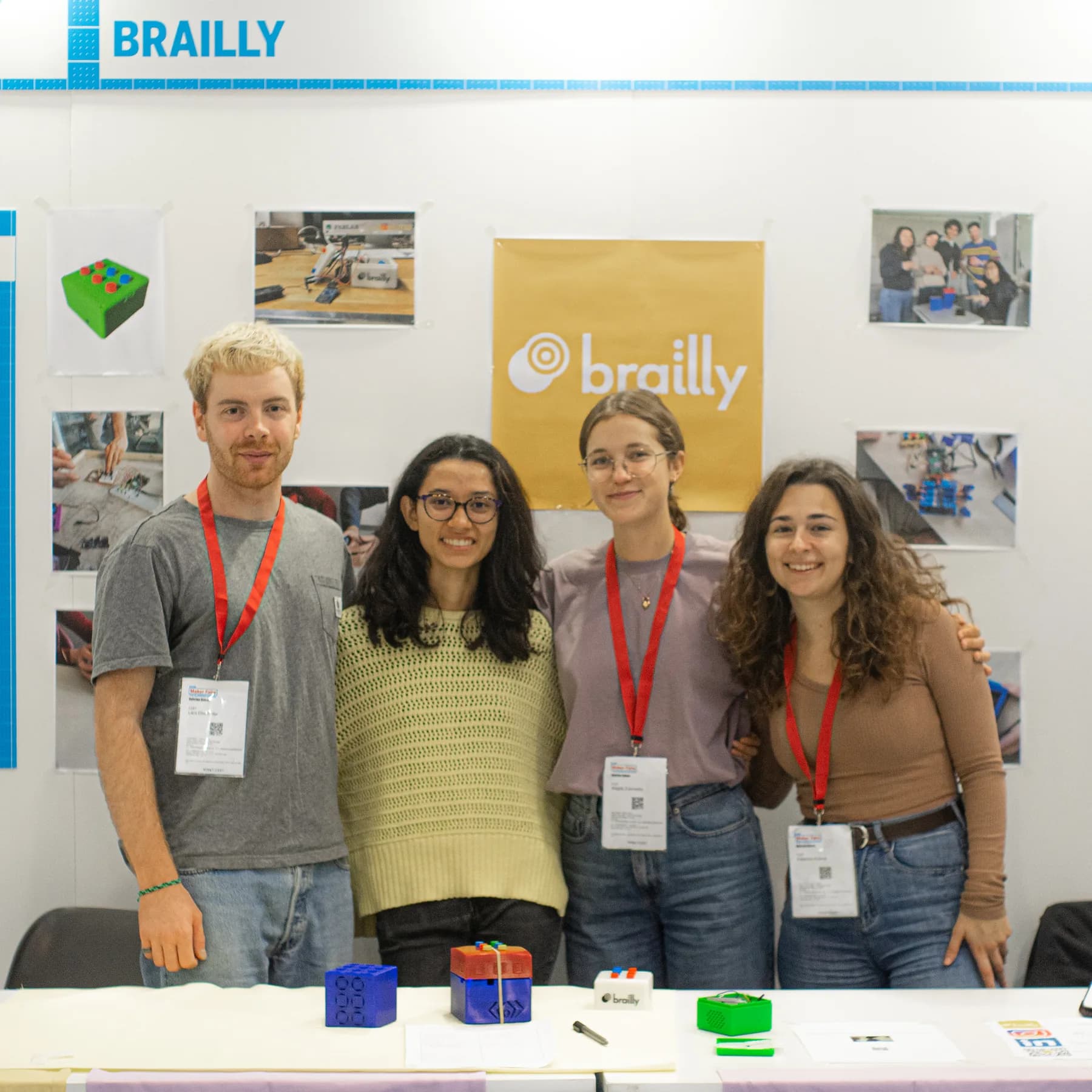 Four Brailly team members standing behind several generations of tactile prototypes at Maker Faire